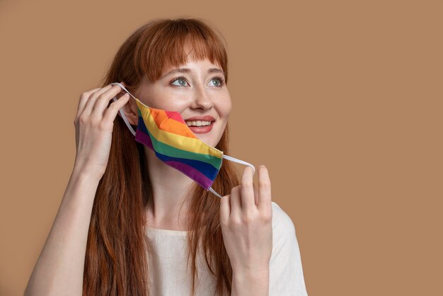 虹の医療マスクを持つ若い赤毛の女性