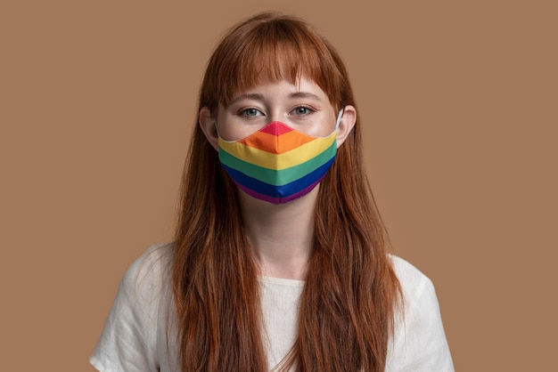 Giovane donna di redhead con mascherina medica arcobaleno