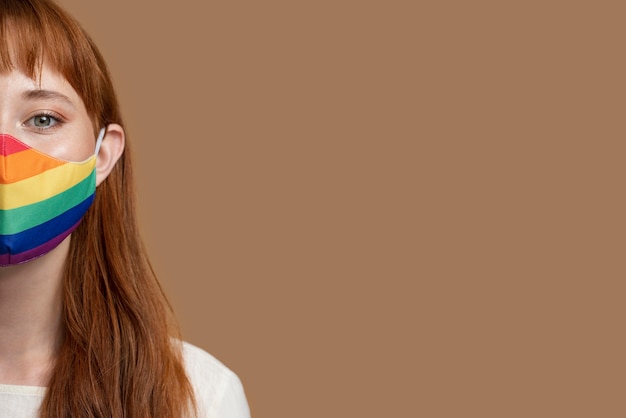 Young redhead woman with rainbow medical mask