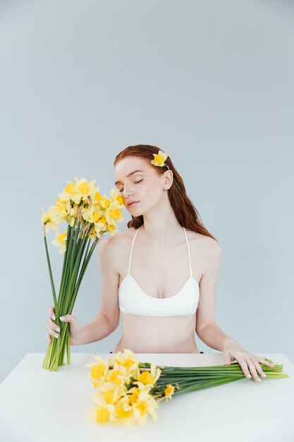 Young redheaded woman holding two bouquets of narcisuss