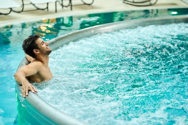 웰빙 센터에서 하루를 보내는 동안 온수 욕조에서 즐기는 젊은 편안한 남자