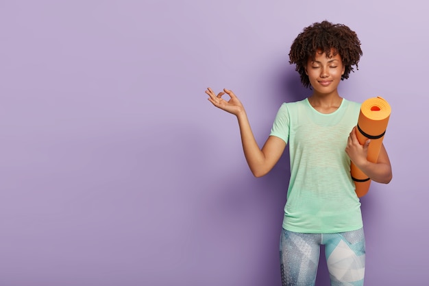 Young relaxed woman practices yoga with karemat