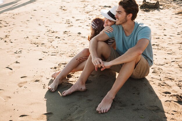 Young romantic couple sitting on the sand