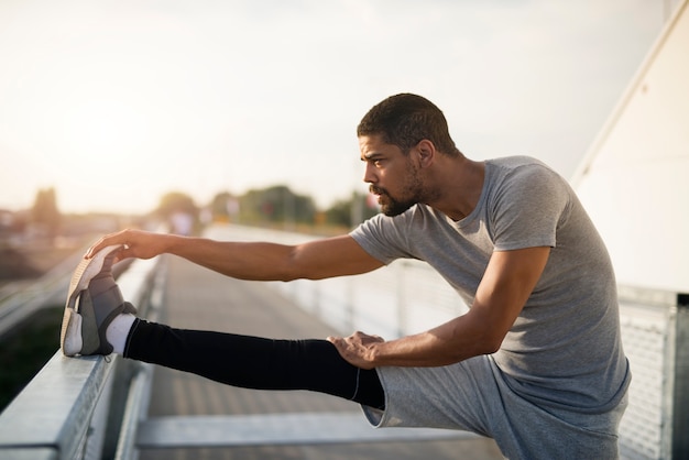 Foto gratuita giovane corridore sportivo che allunga le gambe e si riscalda per correre