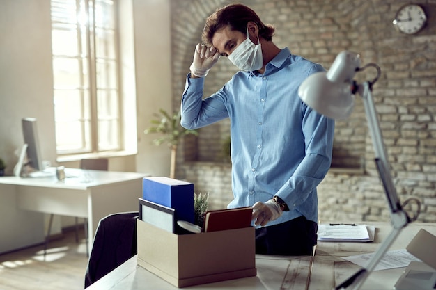 Young sad businessman packing his belongings after being fired during COVID19 pandemic