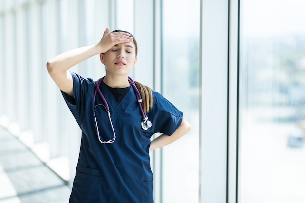 Young sad female nurse at hospital corridor