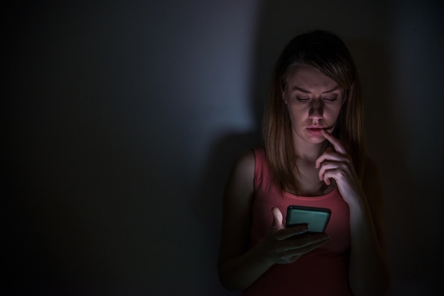 Бесплатное фото Молодая грустная уязвимая девушка, использующая мобильный телефон, испугалась и отчаянно страдает от онлайн-злоупотреблений, киберзапугивание преследуется и подвергается преследованиям в концепции кибербеллинга подростков
