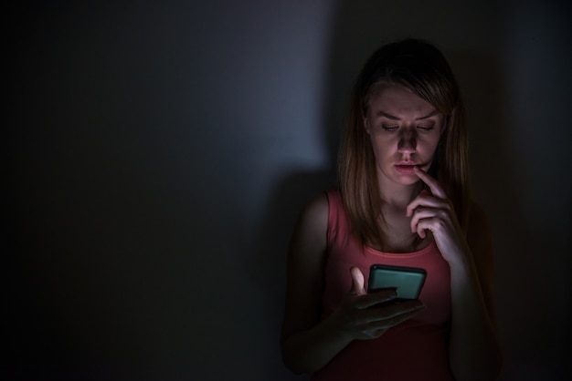 young sad vulnerable girl using mobile phone scared and desperate suffering online abuse cyberbullying being stalked and harassed in teenager cyber bullying concept