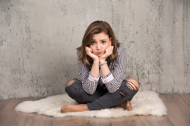 A young sad woman in plaid shirt blowing her cheeks.