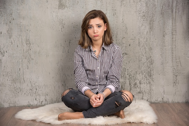 Free photo a young sad woman in plaid shirt blowing her cheeks.