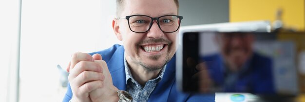 Young satisfied male business coach clenching his hands into fist in front of mobile phone