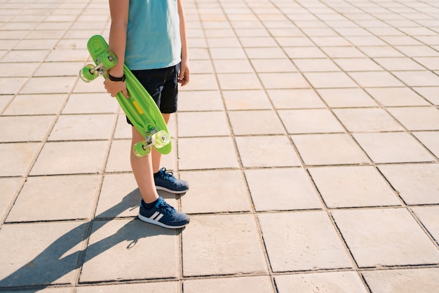 Young SCHOOL cool BOY legs walking with PENNY BOARD in the hands