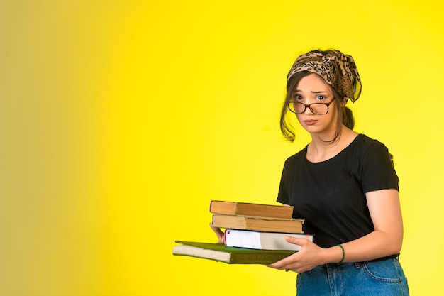 Young schoolgirl in eyeglasses holding her books and looking innocently.