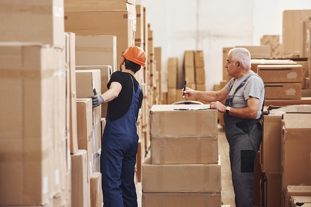 Young and senior storage workers in uniform works together in the warehouse. Premium Photo