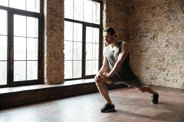 Free photo young serious sports man warming up at the gym