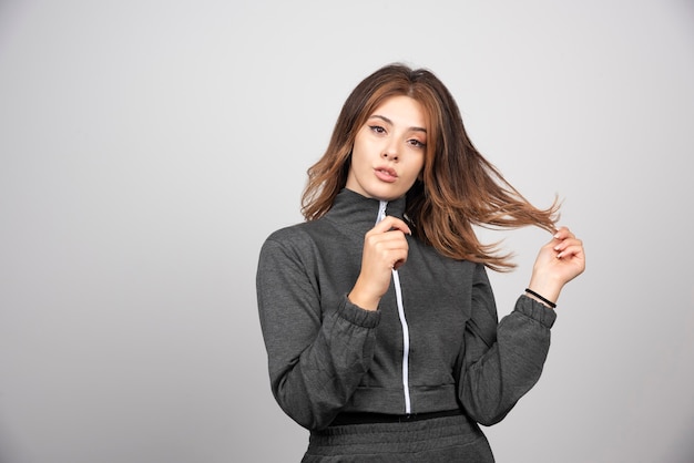 Young serious woman standing and touching hair .