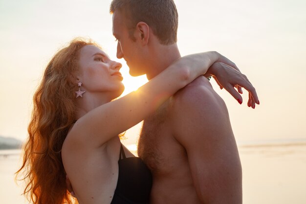 Молодая сексуальная романтическая влюбленная пара счастлива на летнем пляже, вместе веселясь в купальных костюмах