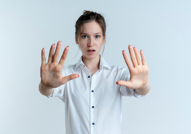 Young shocked blonde russian girl gestures stop with two hands isolated on white space with copy space