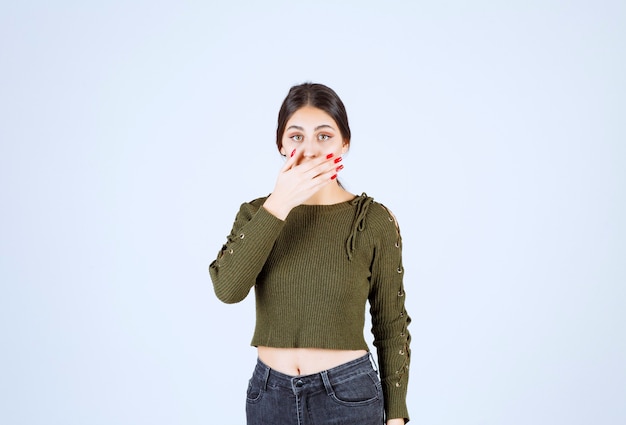 young shocked woman model covering mouth with a hand.