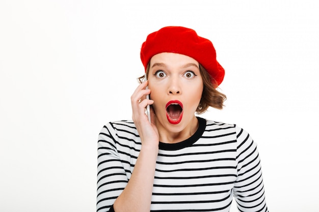 Young shocked woman talking by mobile phone