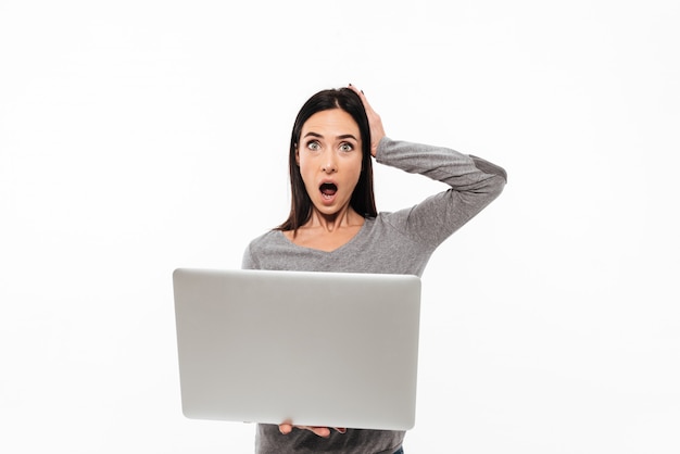 Молодая женщина шокирован, используя портативный компьютер.