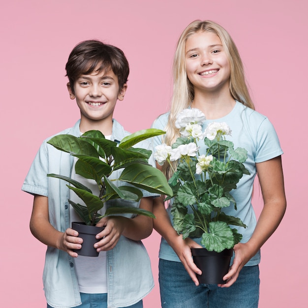 Free photo young siblings holding flowers pot