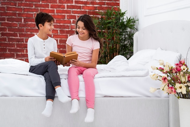 Young siblings at home on bed riding