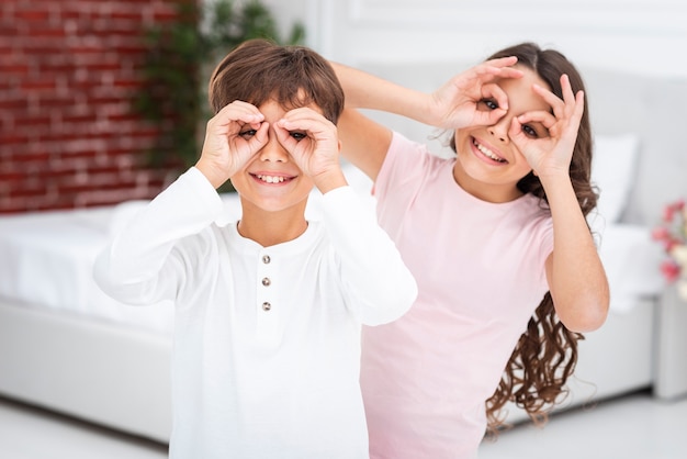 Free photo young siblings making binocular with hands