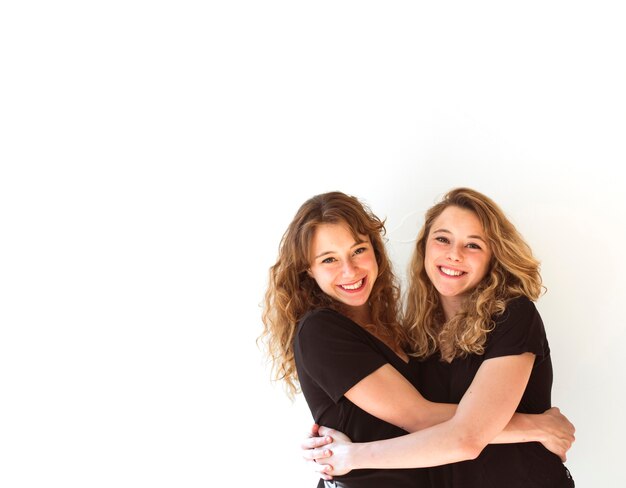 Young sister hugging each other against white background