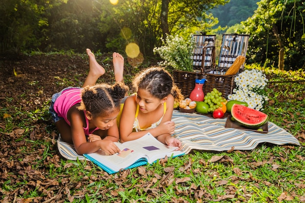 無料写真 ピクニックの布で読む若い姉妹