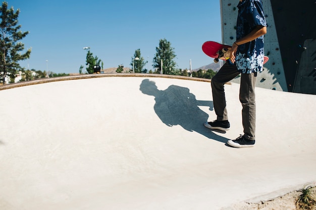 Foto gratuita giovane pattinatore che tiene il suo skateboard