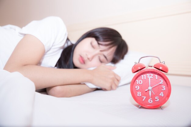 Young sleeping woman and alarm clock in bedroom at home 