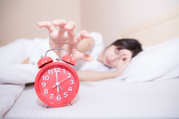 Young sleeping woman and alarm clock in bedroom at home 