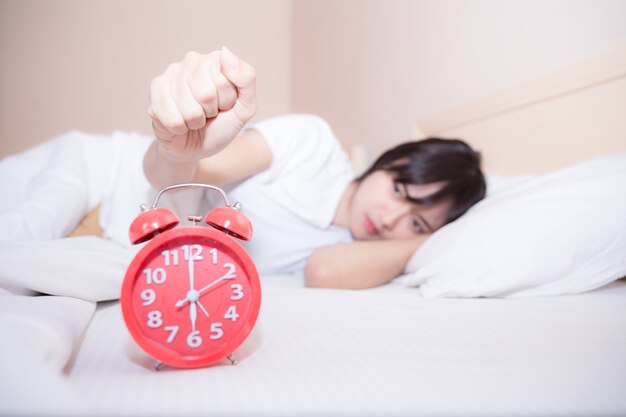 Young sleeping woman and alarm clock in bedroom at home 