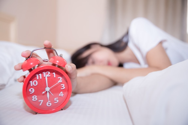 Young sleeping woman and alarm clock in bedroom at home 