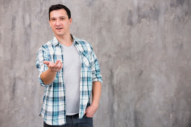 Free photo young slightly smiling guy pointing at camera