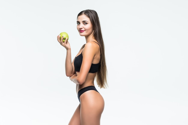 Young slim woman holding red apple. Isolated on white wall. Concept of healthy food and the control of excess weight.