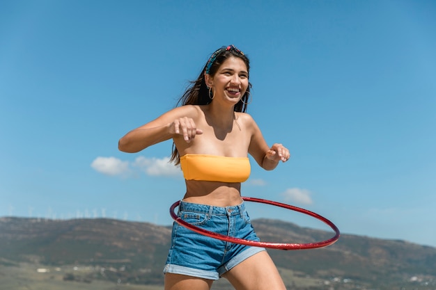 Foto gratuita giovane donna sottile che gira hula hoop intorno alla vita