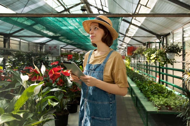 Free photo young smiley woman working in a greenhouse