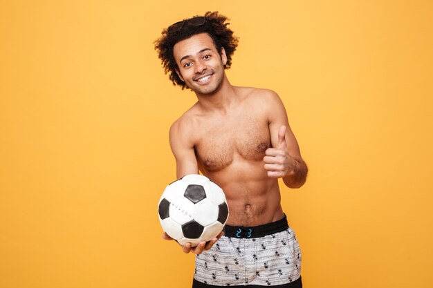 サッカーを保持している夏の服の若い笑顔アフリカ男