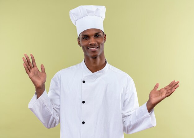 요리사 유니폼에 젊은 미소 아프리카 계 미국인 요리사 보유 손을 녹색 벽에 고립 된 오픈