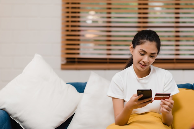 Young smiling Asian woman using smartphone buying online shopping 