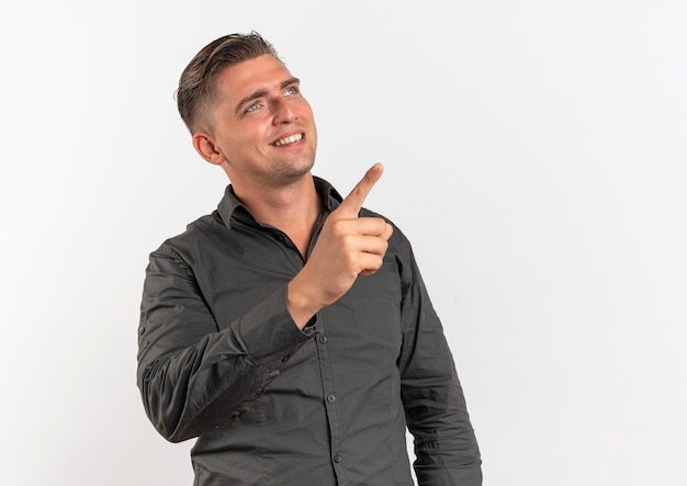 Young smiling blonde handsome man looks and points at side isolated on white background with copy space