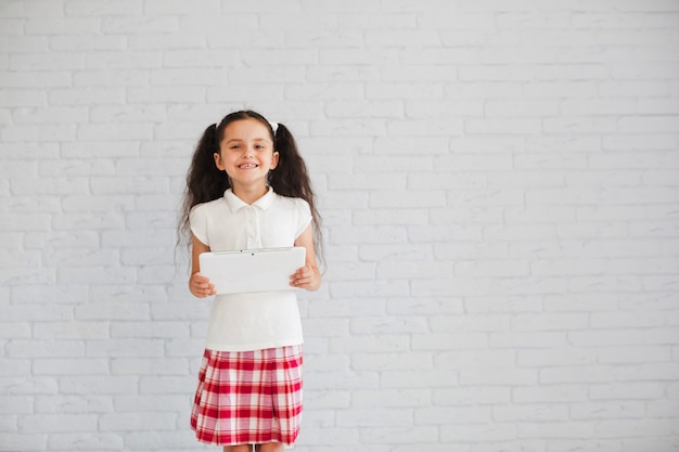 Young smiling brunette girl holding tablet