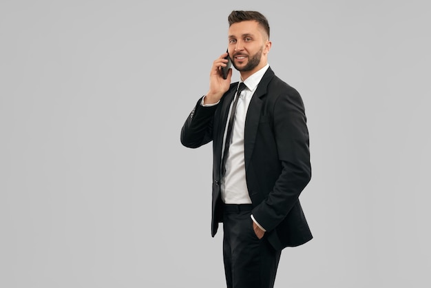 Молодой улыбающийся бизнесмен разговаривает по телефону