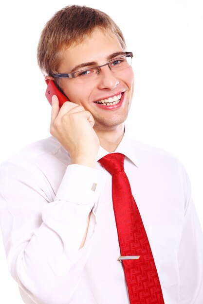 Молодой усмехаясь бизнесмен используя сотовый телефон