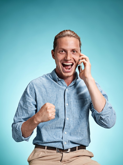 Free photo the young smiling caucasian man on blue background