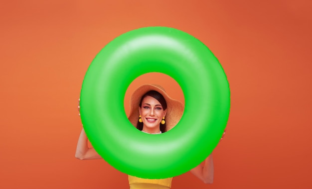 Free photo young smiling cheerful tourist woman wear hat hold inflatable ring isolated on orange background