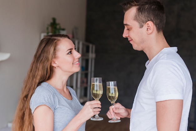 Young smiling couple clanging glasses at home