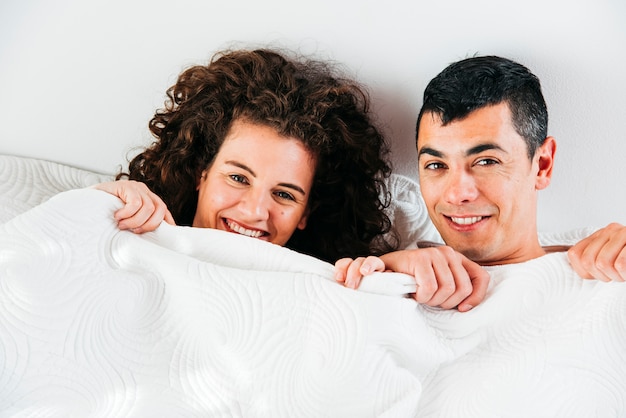 Молодая улыбающаяся пара под одеялом